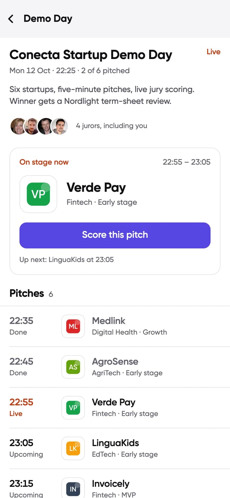 Conecta Demo Day screen: the startup on stage now, a Score this pitch button and the pitch running order